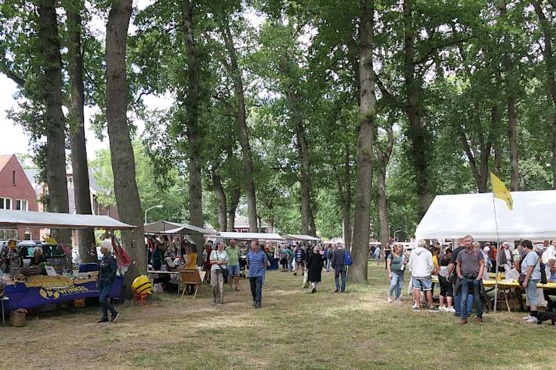 Doorkijkje naar de marktkramen onder de bomen en de tent van het Bijkersgilde